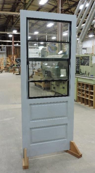 Half lite self-storing wood storm door with a black insert, interior view