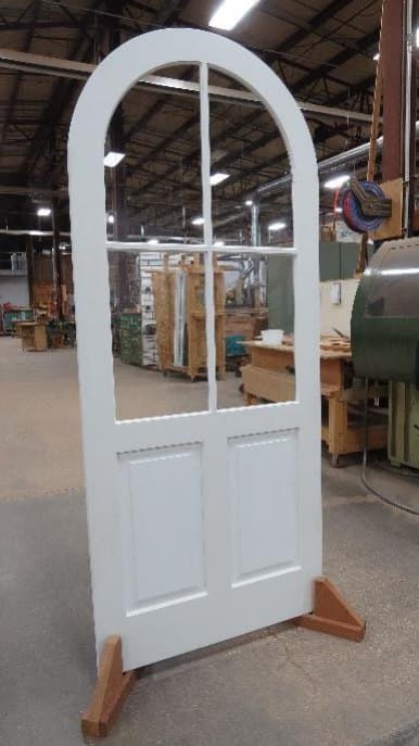 Painted half lite wood storm door with divided lites and an arched top