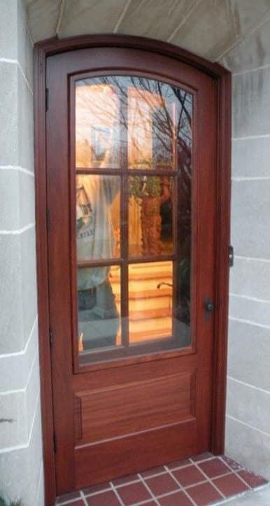 Stained 2/3 lite arched-top wood storm and screen door installed at a brick entry