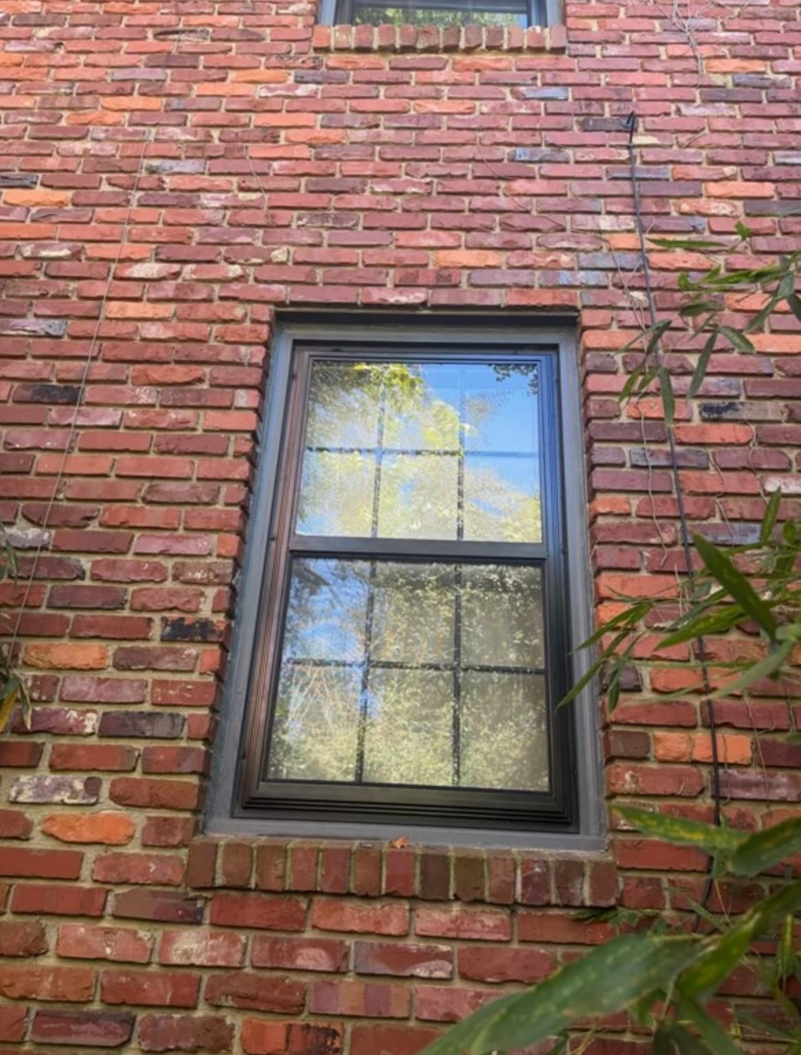 Single black two-track storm window installed on a brick home