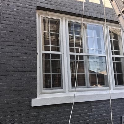 Three fitted storm windows on a painted brick facade