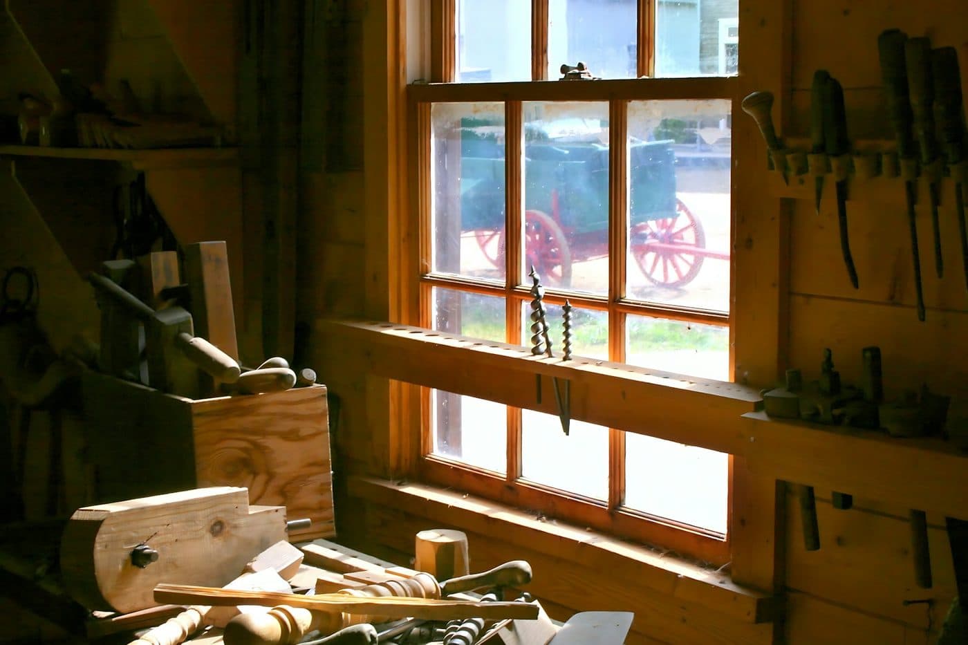 A sunlit wooden workshop with a window above the workbench