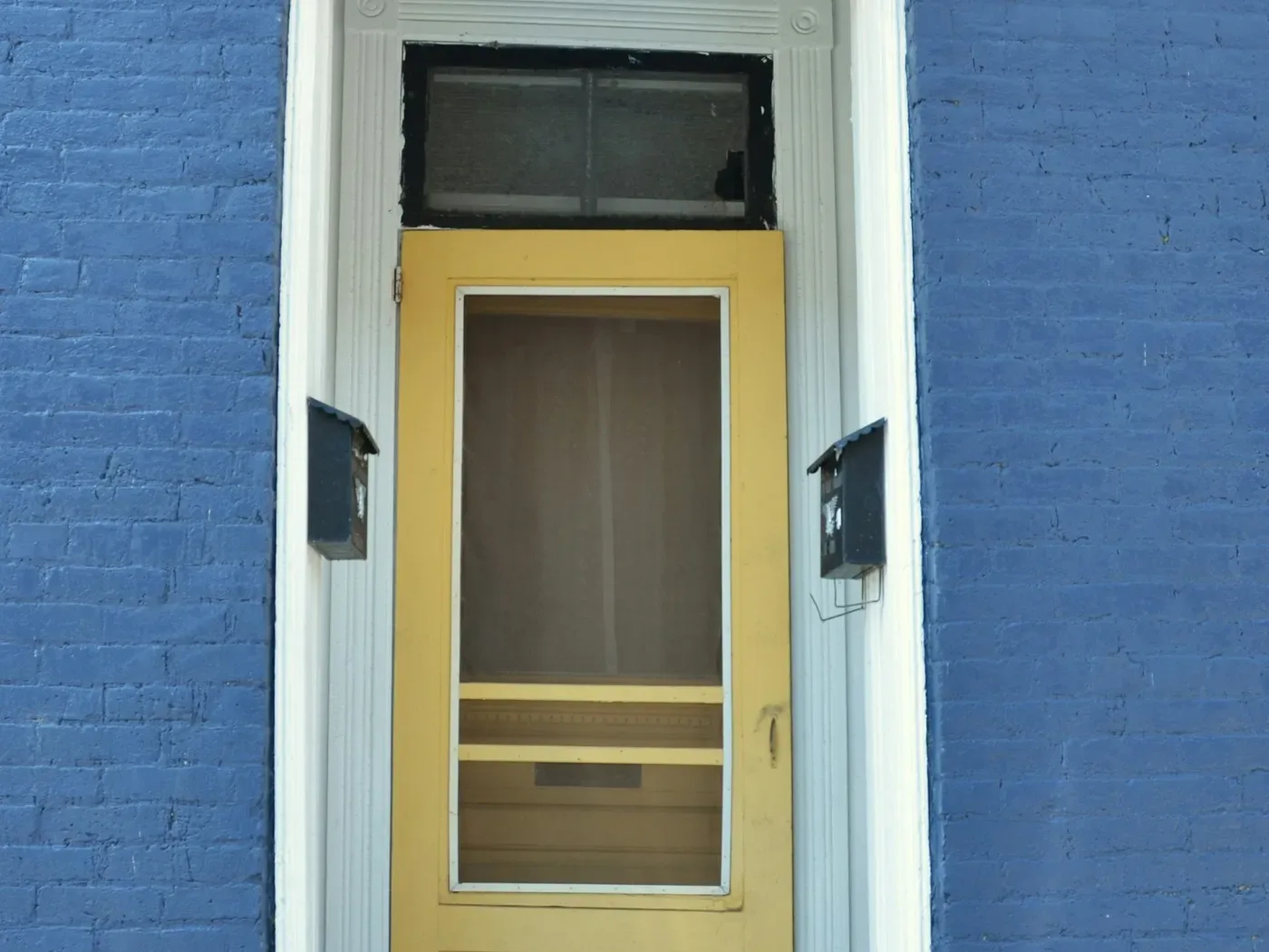 A door set in a painted trim surround on a brick wall