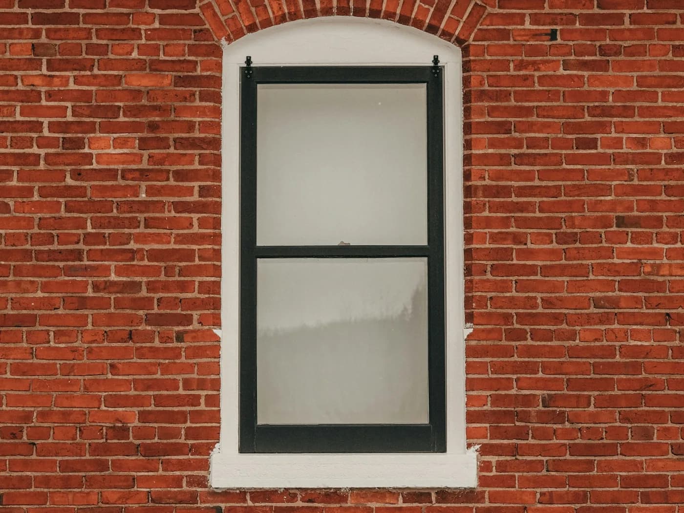 A window set back inside a brick opening, with a ledge around it