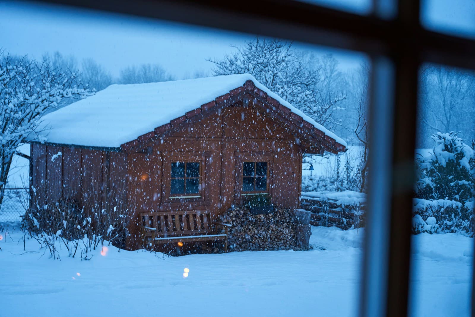 Snow falling outside a warm cabin window